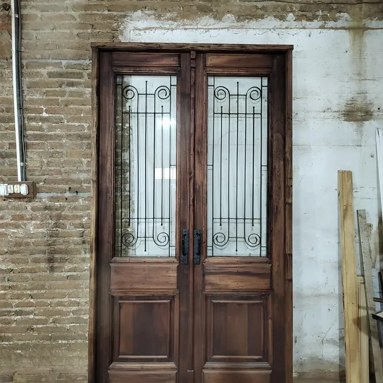 Puerta colonial de dos hojas con rejas artesanales en una casa de ladrillo