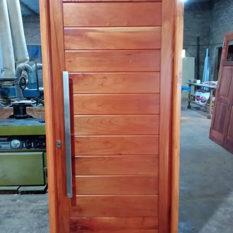 Puerta de frente entablonada recién terminada en el taller de Humboldt, con las máquinas atrás