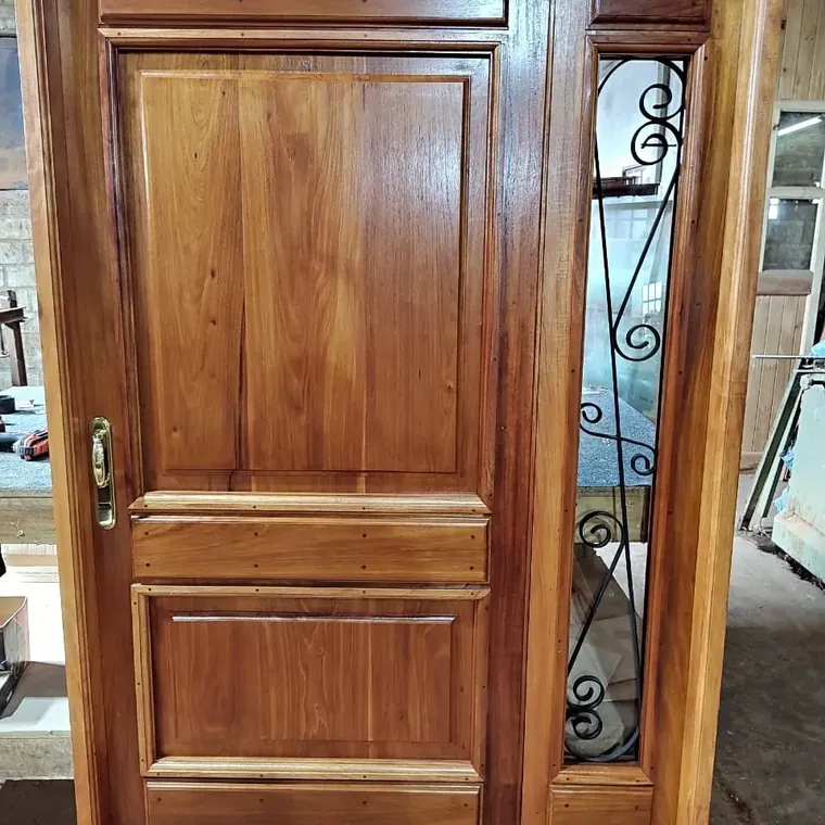 Puerta de frente con tablero y paño lateral con reja artesanal